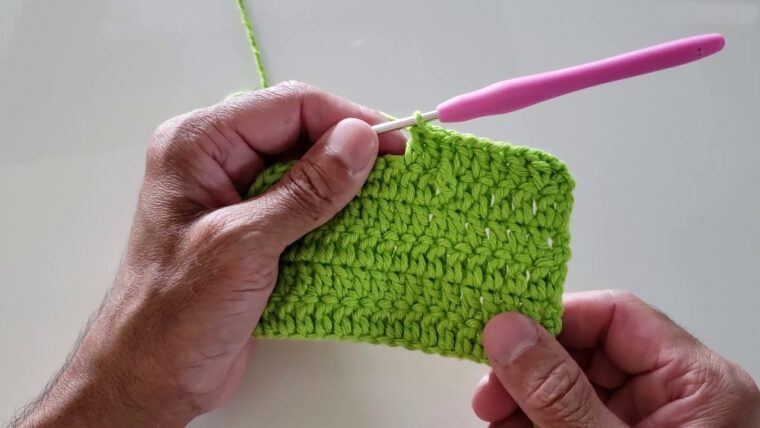 Detalhe de trabalho manual em crochê: detalhe mostrando como melhorar o crochê, mãos segurando o trabalho e agulha rosa. — Produzido por Samuel Ramos - Blog do Crochê.