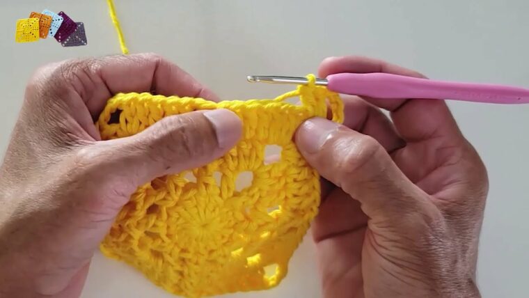 Detalhe de trabalho manual em crochê: Mãos trabalhando crochê com fio de algodão amarelo, utilizando ponto alto e detalhes em pipoca, formando um sousplat redondo. — Produzido por Samuel Ramos - Blog do Crochê.