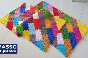 Detalhe de trabalho manual em croch&ecirc;: Tapete retangular de croch&ecirc; com pontos pipoca, feito com fio de algod&atilde;o colorido em padr&atilde;o geom&eacute;trico, predominando tons vibrantes como azul, amarelo, vermelho e verde. &mdash; Produzido por Samuel Ramos - Blog do Croch&ecirc;.