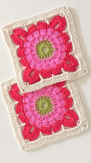 Dois quadrados de crochê artesanal com um desenho de flor em camadas: centro verde, pétalas rosa claro e contorno vermelho, finalizados com uma moldura de pontos altos em linha branca sobre um fundo neutro.